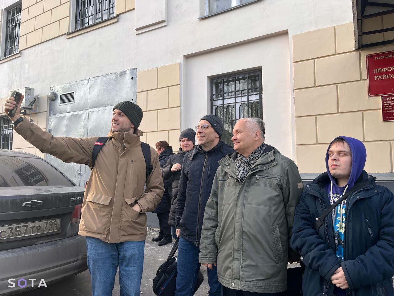 Фото: Роман Юнеман на выходе из суда снимает своего научрука Андрея Суздальцева (третий слева)